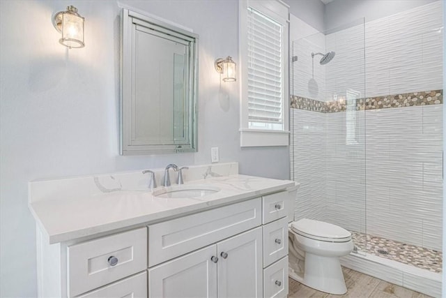 full bathroom featuring toilet, a tile shower, and vanity