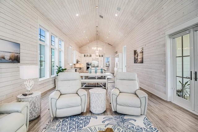 interior space with high vaulted ceiling, light wood-style flooring, wood walls, wood ceiling, and an inviting chandelier