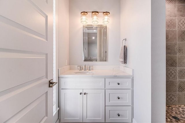 full bath with a tile shower and vanity