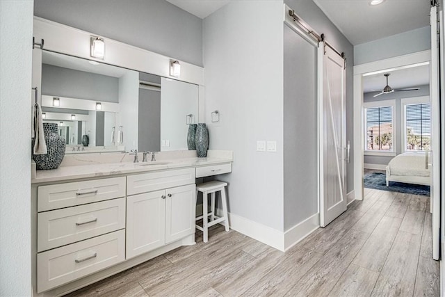 ensuite bathroom with ceiling fan, baseboards, and wood finished floors