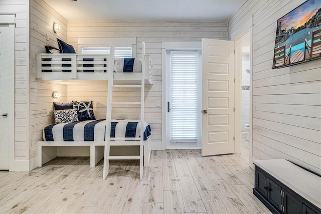 bedroom featuring light wood-type flooring and wooden walls