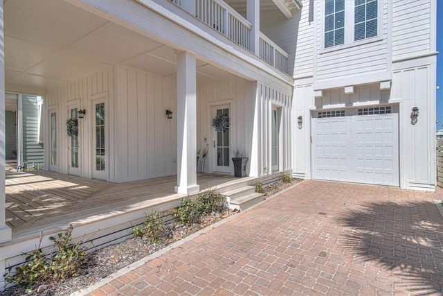 doorway to property featuring a garage, decorative driveway, and board and batten siding