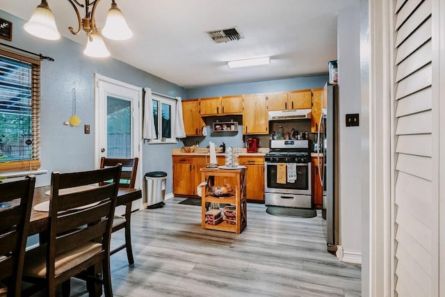 10910 Stacy, Corpus Christi, TX 78410 - kitchen with stainless steel gas stove, under cabinet range hood, light wood-style flooring, and light countertops