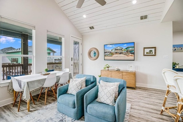 living area featuring light wood finished floors, visible vents, baseboards, and vaulted ceiling