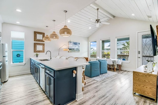 kitchen with vaulted ceiling with beams, light wood-style flooring, appliances with stainless steel finishes, a peninsula, and a sink