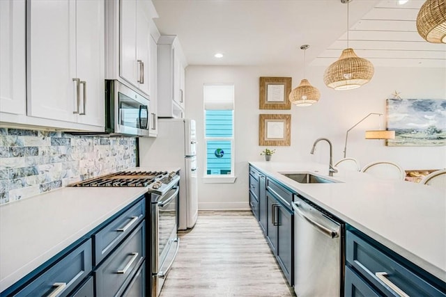 kitchen featuring tasteful backsplash, light countertops, appliances with stainless steel finishes, white cabinetry, and a sink