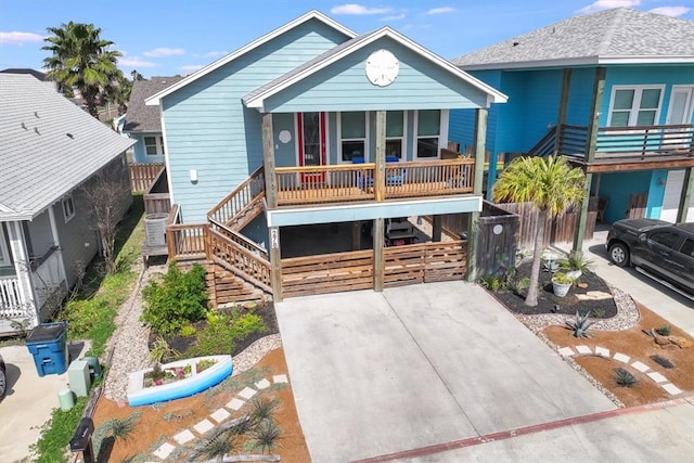 view of front of house featuring a carport, covered porch, concrete driveway, and stairs