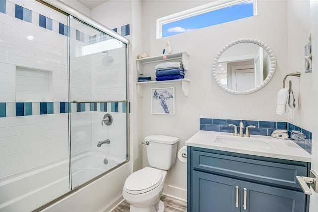 bathroom featuring combined bath / shower with glass door, toilet, vanity, and baseboards