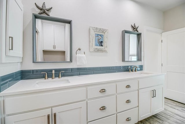 full bathroom with double vanity, wood finished floors, and a sink