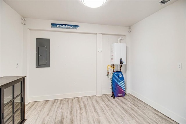 unfurnished room with electric panel, baseboards, tankless water heater, and light wood-style floors