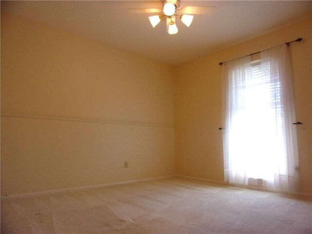 empty room with a ceiling fan, light carpet, and plenty of natural light