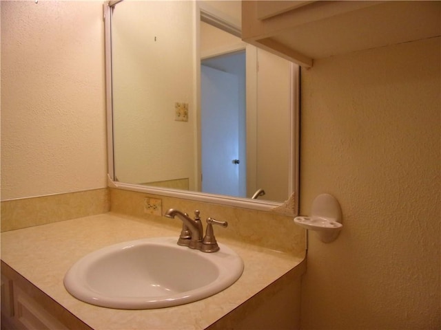 bathroom with a textured wall and vanity