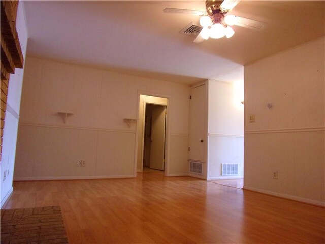 empty room featuring a ceiling fan, visible vents, and light wood finished floors