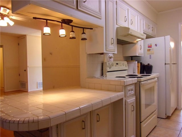 kitchen featuring under cabinet range hood, electric range, tile counters, tasteful backsplash, and crown molding