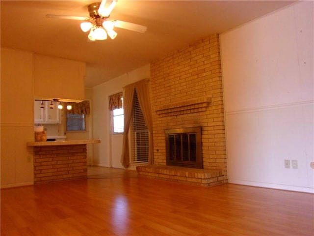 unfurnished living room with ceiling fan, a fireplace, and wood finished floors