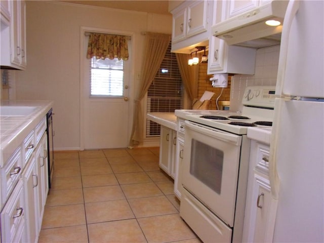 kitchen with light tile patterned floors, under cabinet range hood, white appliances, white cabinets, and tile counters