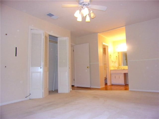 unfurnished bedroom with a closet, visible vents, ensuite bath, carpet, and a sink