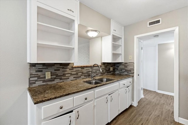 kitchen with white cabinets, sink, dark stone countertops, tasteful backsplash, and dark hardwood / wood-style flooring