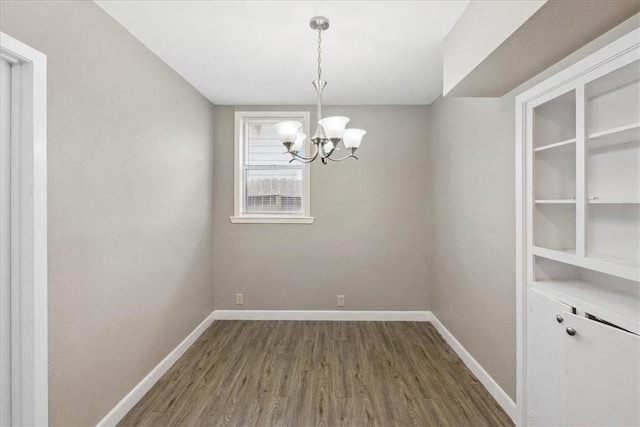 unfurnished dining area featuring dark wood-type flooring and a chandelier