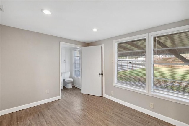 unfurnished bedroom with connected bathroom and wood-type flooring