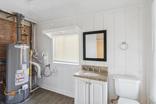 bathroom featuring hardwood / wood-style flooring, vanity, toilet, and gas water heater