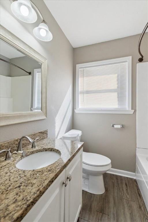 full bathroom featuring hardwood / wood-style flooring, vanity, toilet, and shower / bathing tub combination