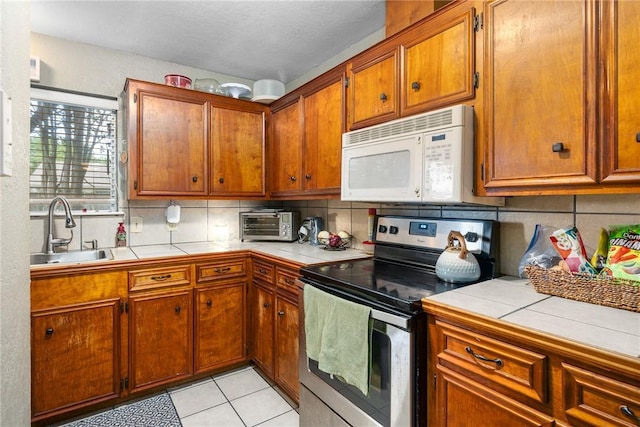 3713 Tripoli Dr, Corpus Christi, TX 78415 - kitchen featuring electric stove, white microwave, tile counters, decorative backsplash, and brown cabinets