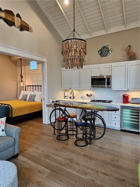 kitchen with pendant lighting, white cabinetry, stainless steel appliances, and hardwood / wood-style flooring