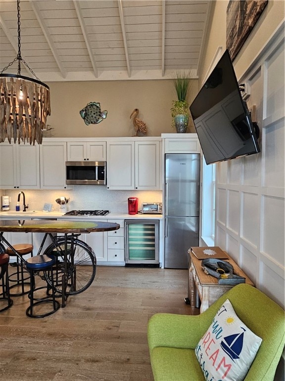 kitchen featuring white cabinets, pendant lighting, stainless steel appliances, and beverage cooler