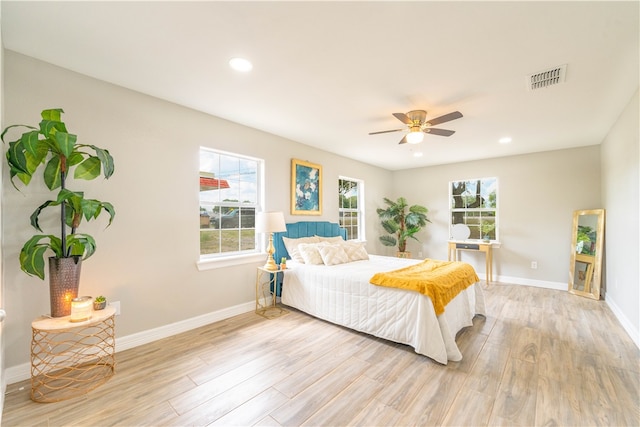 bedroom featuring light hardwood / wood-style floors, ceiling fan, and multiple windows