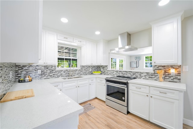 kitchen with white cabinets, wall chimney exhaust hood, stainless steel range with electric stovetop, and sink