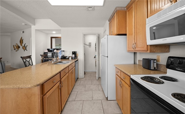 kitchen with a textured ceiling, white appliances, light tile patterned floors, and sink