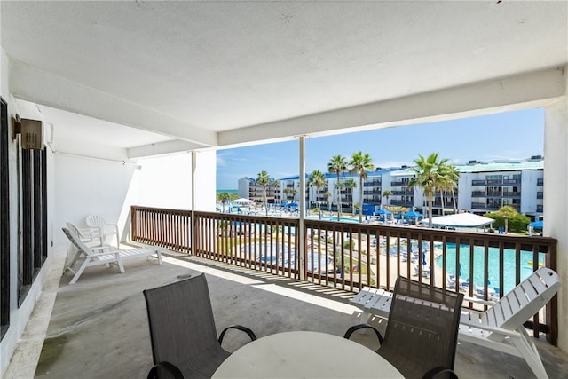 view of patio featuring a community pool, a balcony, and a water view