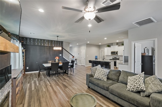 living room featuring light hardwood / wood-style floors, ceiling fan, and sink