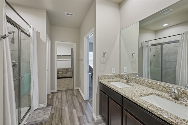 bathroom with hardwood / wood-style flooring, vanity, and a shower with shower door