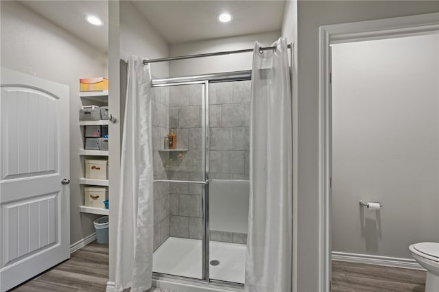 bathroom with hardwood / wood-style flooring, toilet, and a tile shower