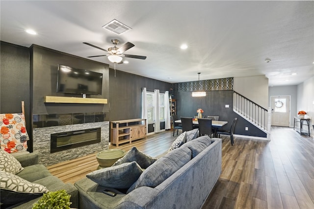 living room with hardwood / wood-style flooring, ceiling fan, and a stone fireplace