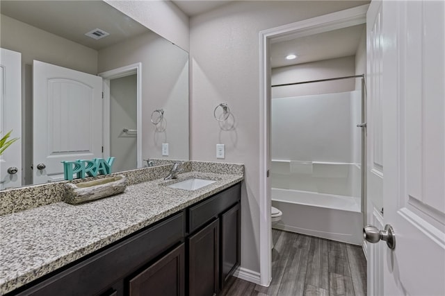 full bathroom with hardwood / wood-style floors, vanity, shower / bathtub combination, and toilet