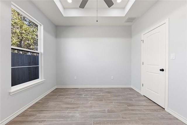 unfurnished room featuring a tray ceiling, light hardwood / wood-style flooring, and ceiling fan