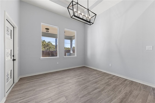 unfurnished room featuring a notable chandelier and light hardwood / wood-style floors