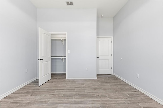 unfurnished bedroom featuring a walk in closet, a closet, and light wood-type flooring