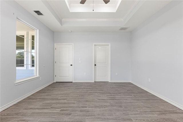 spare room featuring ceiling fan, ornamental molding, a raised ceiling, and light hardwood / wood-style flooring