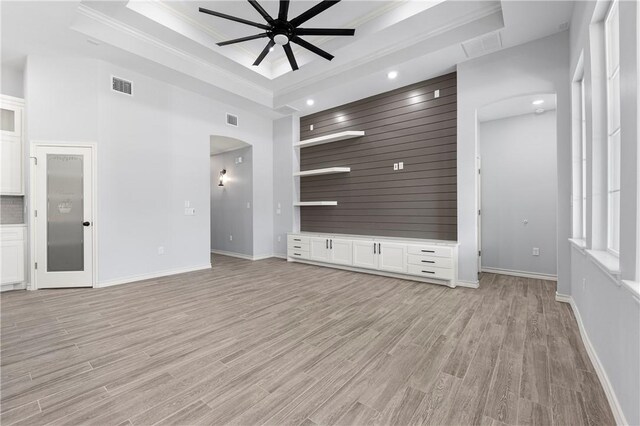 unfurnished living room featuring a high ceiling, a raised ceiling, ceiling fan, and light wood-type flooring