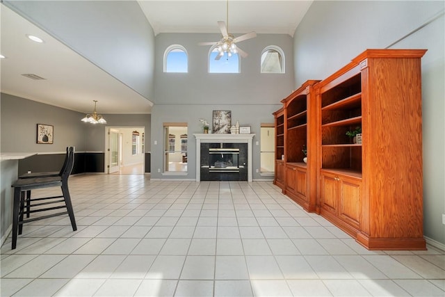 unfurnished living room featuring crown molding, ceiling fan, a fireplace, and a towering ceiling