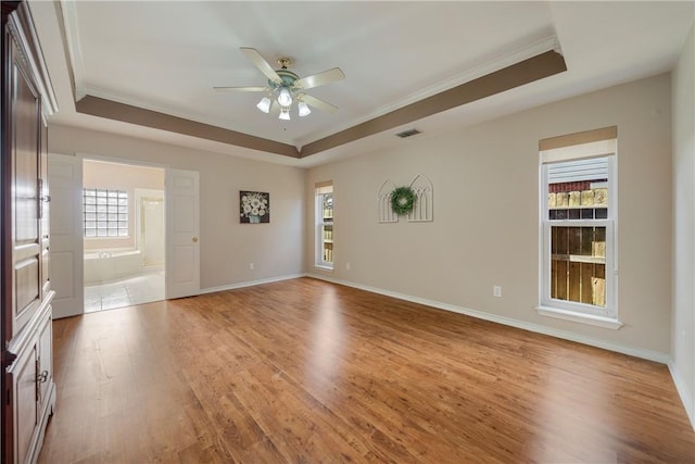 unfurnished room with ornamental molding, a raised ceiling, and light hardwood / wood-style floors