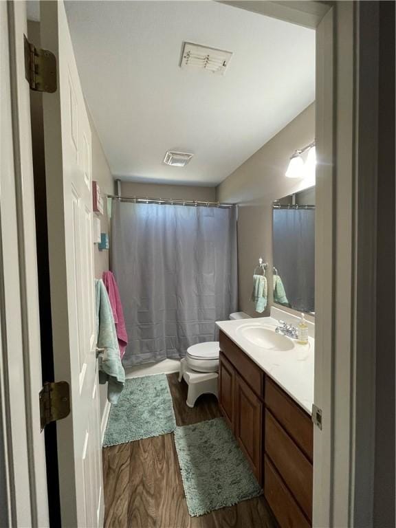 full bath featuring curtained shower, visible vents, toilet, wood finished floors, and vanity