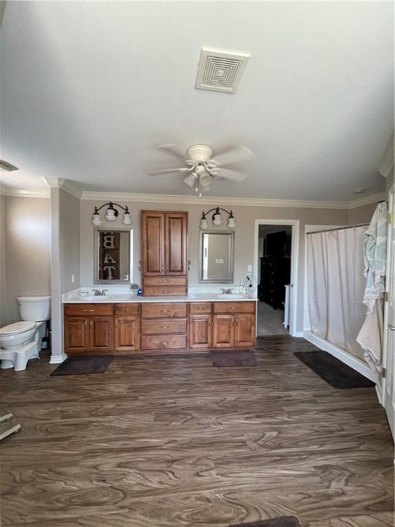 bathroom with ceiling fan, toilet, double vanity, visible vents, and ornamental molding