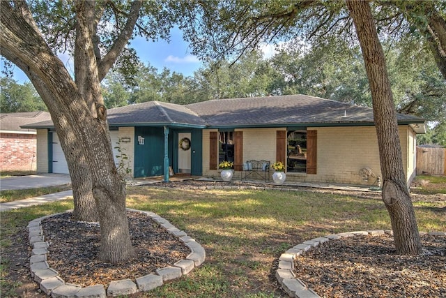 ranch-style home featuring a garage, covered porch, and a front lawn