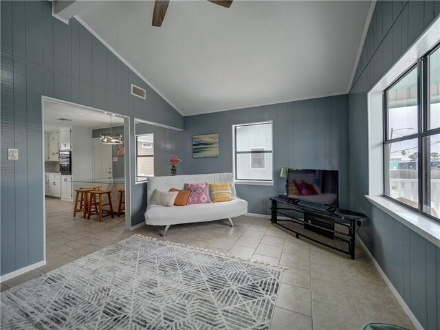 tiled living area featuring a ceiling fan, crown molding, baseboards, and wood walls