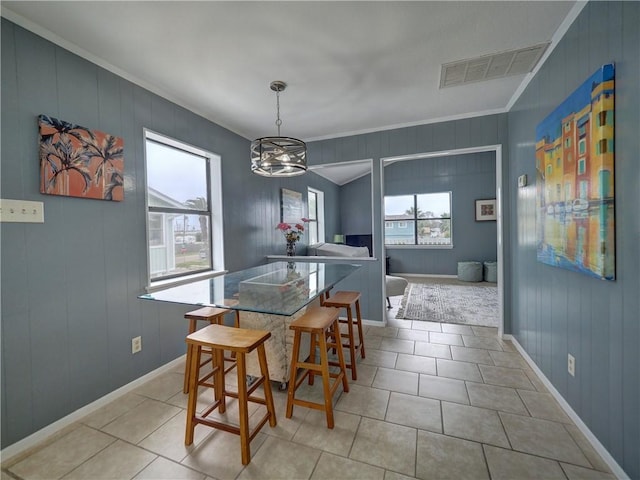 dining area featuring crown molding, light tile patterned floors, a chandelier, and baseboards